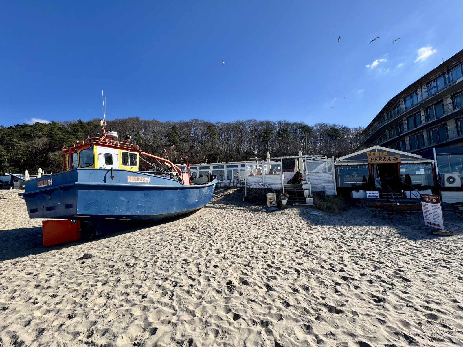 Baltic beach with a fishing boat on clear winter sand